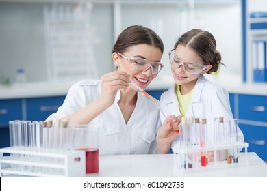 portrait of smiling girl student watching scientist teacher making experiment in lab - Powered by Shutterstock