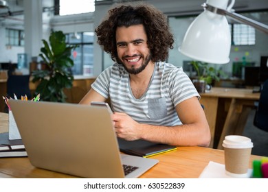 Portrait Of Smiling Graphic Designer Using Mobile Phone In Creative Office