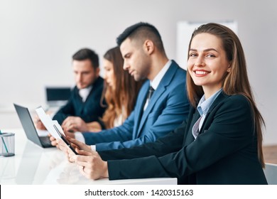 Portrait Of Smiling Group Of Business People Sitting In A Row Together At Table In A Modern Office. Business Team  Concept                            