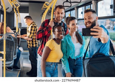 Portrait of a smiling group of diverse friends riding together on a bus and taking a selfie with a smartphone. Multiracial group of people enjoying travel or ride on public vehicle and having fun. - Powered by Shutterstock