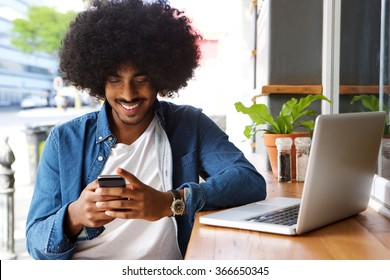 Portrait Of A Smiling Guy Using Mobile Phone And Laptop