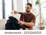 Portrait of smiling, handsome bearded man, business man put things together in backpack, holding laptop, sitting in cafe. Business concept