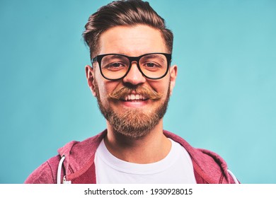 Portrait of smiling Handsome bearded young hipster man with glasses on blue background
