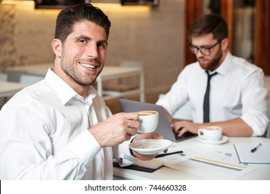 Portrait eines lächelnden gut aussehenden Geschäftsmanns, der mit seinem männlichen Kollegen Kaffee trinkt