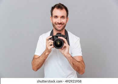 Portrait Of A Smiling Handsome Man Holding Camera Isolated On A Gray Background