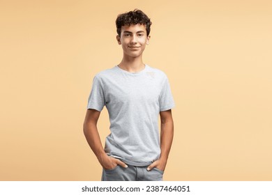 Portrait of smiling handsome teenage boy wearing casual clothes looking at camera posing on beige background. Advertisement concept - Powered by Shutterstock