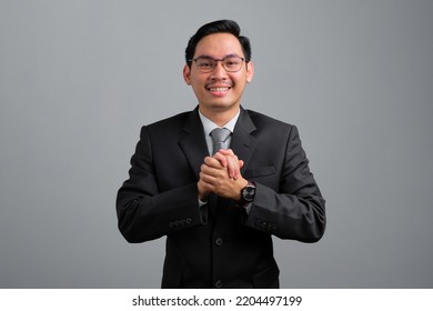 Portrait of smiling handsome young businessman in formal suit clapping hands and looking at camera isolated on grey background - Powered by Shutterstock