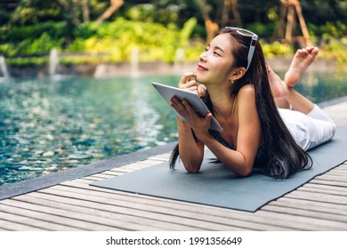 Portrait Of Smiling Happy Beauty Asian Freelancer Traveler Blogger Woman Relax Using And Work Technology Of Tablet Computer In Swimming Pool On Summer Travel Vacation Relaxing At Resort Spa