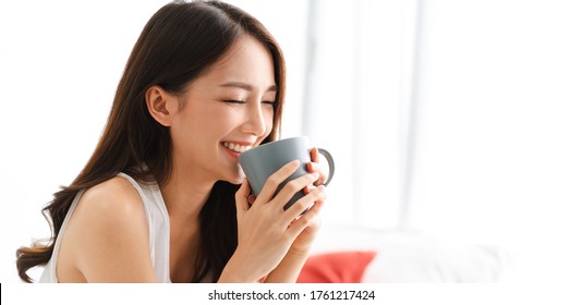 Portrait of smiling happy cheerful beautiful pretty asian woman relaxing drinking and looking at cup of hot coffee or tea.Girl felling enjoy having breakfast in holiday morning vacation on bed at home - Shutterstock ID 1761217424