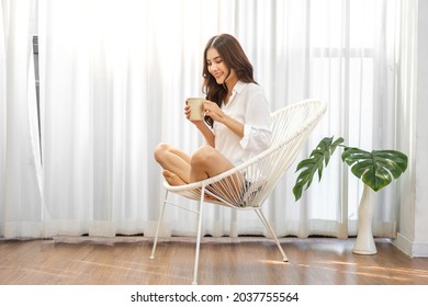 Portrait of smiling happy cheerful beautiful pretty asian woman relaxing drinking and looking at cup of hot coffee or tea.Girl felling enjoy having breakfast in holiday morning vacation on bed at home - Powered by Shutterstock