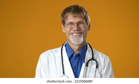 Portrait Of Smiling Happy Confident Mature Man Medical Doctor On Solid Yellow Background.