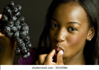 Portrait Of Smiling Happy Pretty Sexy Young Latin Puerto Rican Black  Woman Eating Healthy Food Fresh Fruit Grapes