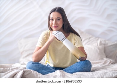 Portrait Smiling Happy Woman With Prosthetic Arm Sitting On Bed At Home, Girl With Disability Artificial Prosthetic Limb