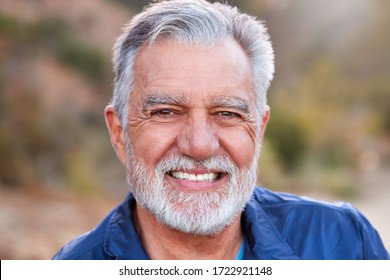 Portrait Of Smiling Hispanic Senior Man Outdoors In Countryside