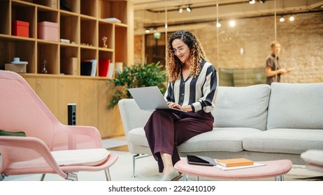 Portrait of Smiling Hispanic Woman Working on a Laptop in a Meeting Room at Office. Female Team Lead Smiling After Fulfilling an Important Task. E-commerce Specialist Researching on the Web - Powered by Shutterstock