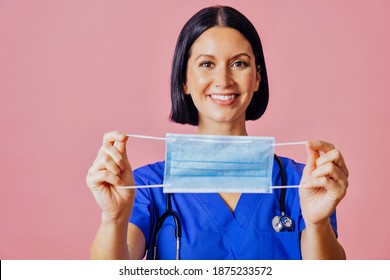 Portrait Of A Smiling Hospital Nurse Holding A Face Mask  To Indicate Everyone Must Cover Nose And Mouth, Isolated On Copy Space