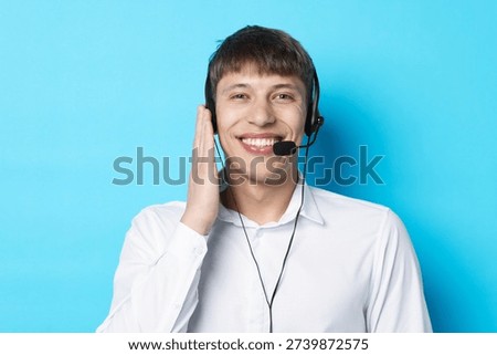 Portrait of smiling hotline operator in headset on light blue background