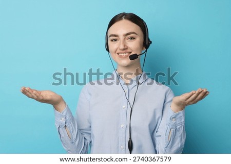 Portrait of smiling hotline operator in headset on light blue background