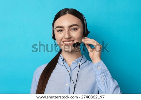 Portrait of smiling hotline operator in headset on light blue background