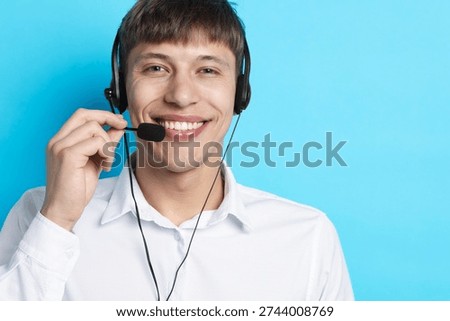 Portrait of smiling hotline operator in headset on light blue background. Space for text