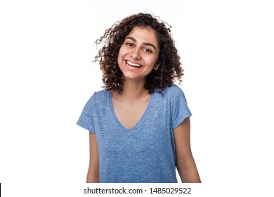Portrait of a smiling Indian brunette young woman. Joyful mixed race girl on a white isolated background. Happy female in t-shirt with a shaggy hairstyle. 