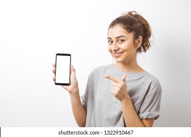 Portrait of a Smiling Indian Girl pointing finger on the white screen of the smartphone.