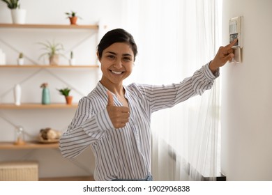 Portrait of smiling indian lady use domestic fire alarm system switch button on wall keypad show thumb up. Young female satisfied user of home security equipment look at camera trust recommend safety - Shutterstock ID 1902906838
