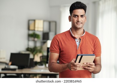 Portrait Of Smiling Indian Software Developer With Digital Tablet Standing In Office