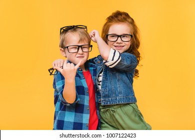 Portrait Of Smiling Kids In Eyeglasses Isolated On Yellow