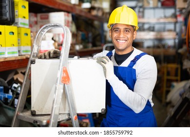 Portrait Of Smiling Latin American Foreman Standing With Tool Case In Building Materials Store