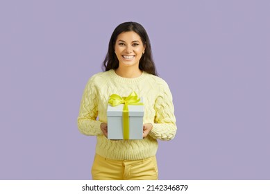 Portrait Of Smiling Latino Girl Isolated On Violet Studio Background Hold Present For Birthday Or Anniversary. Happy Ethnic Young Woman Worth Gift Box In Hands. Party And Celebration, Bonus Concept.