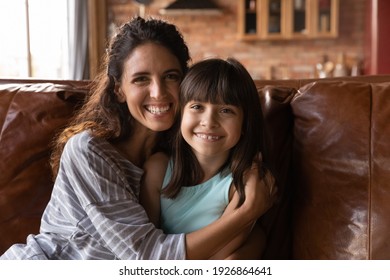 Portrait of smiling Latino mother and little biracial daughter hug cuddle show love and care. Happy Hispanic mom and small 8s girl child embrace feeling grateful thankful. Family bonding concept.