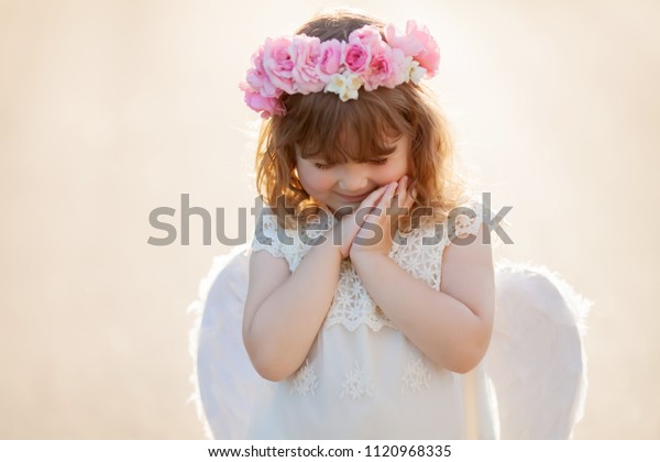 バラの花輪を持つ微笑む小さく巻き毛のある天使の女の子のポートレート 天使のような性格の子ども 天使の衣装を着た幼い女の子 白いドレスと羽の翼 無実の 子どものコンセプト の写真素材 今すぐ編集 バラの花輪を持つ微笑む小さく巻き毛のある天使の女の子のポートレート 天使のような性格の子ども 天使の衣装を着た幼い女の子 白いドレスと羽の翼 無実の 子どものコンセプト の写真素材 今すぐ編集