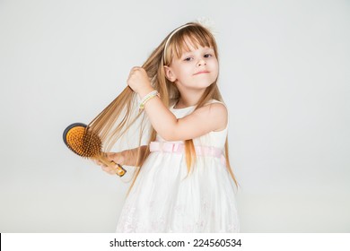 Portrait of smiling little girl brushing her hair closeup