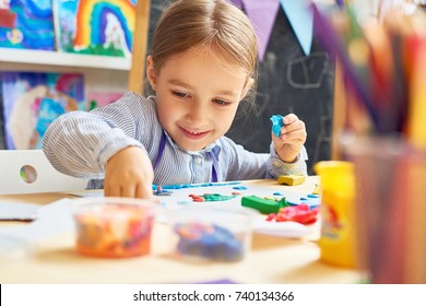 Portrait of smiling little girl working with plasticine in art and craft class of development school