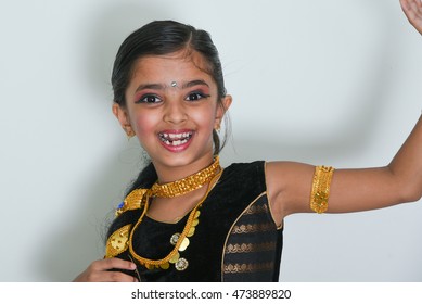Portrait of a smiling little Indian girl/child/kid in dance pose/performing dance dressed up in the its costume, North India. Beautiful Bollywood dancer