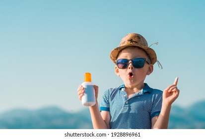 Portrait Of Smiling Little Kid Boy At Tropical Beach Applying Sunblock Cream. Child In Sunglasses And Hat On Sunny Day. Protection From Sunlight. Funny Face.