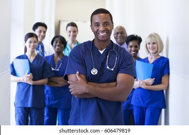 Portrait smiling male African American nurse in uniform scrubs with multi ethnic hospital medical team