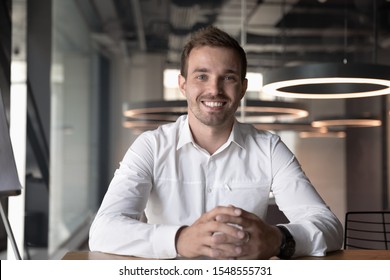 Portrait of smiling male Caucasian employee sit at office desk look at camera in modern office, happy man worker millennial businessman posing, having video call with client or customer online - Shutterstock ID 1548555731