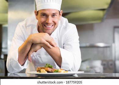 Portrait of a smiling male chef with cooked food standing in the kitchen - Powered by Shutterstock