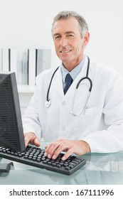 Portrait of a smiling male doctor using computer at the medical office