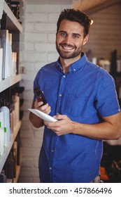 Portrait Of Smiling Male Hair Dresser Selecting Shampoo From Shelf At A Salon