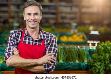 Portrait of smiling male staff standing with arms crossed in organic section of super market - Powered by Shutterstock