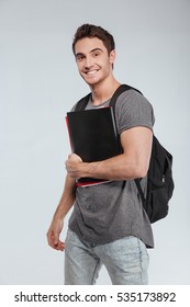 Portrait Of A Smiling Male Student With Backpack And Folders Over White Background