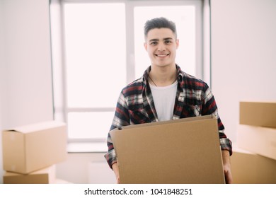 Portrait of a smiling man carrying boxes in new house - Shutterstock ID 1041848251