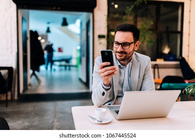 Portrait of smiling man looking at smartphone at the cafe.