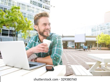 Portrait Of A Smiling Man Sitting Outside With Laptop And Coffee 