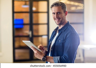 Portrait of smiling man using digital tablet in creative office