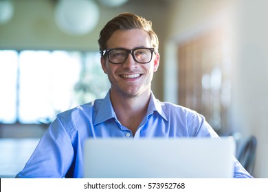 Portrait of smiling man using laptop in restaurant - Powered by Shutterstock