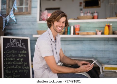 Portrait of smiling man using mobile phone on bench